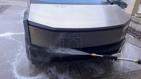 Photo for Denver, Colorado, USA-April 28, 2024- The front end of a Tesla Cybertruck is being meticulously cleaned using a high-pressure washer, showcasing the effectiveness of detailed vehicle maintenance and - Royalty Free Image