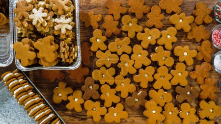 Téléchargez les photos : Home Kitchen Amidst the holiday cheer, a woman in a home kitchen lovingly prepares gingerbread man sandwich cookies, destined to be heartfelt Christmas gifts. Each cookie, with its sweet creamy - en image libre de droit