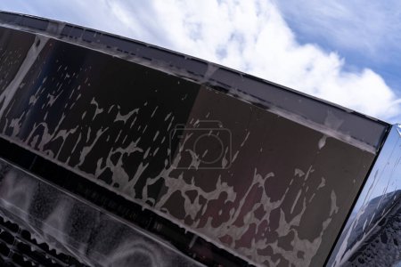 Foto de Denver, Colorado, USA-May 5, 2024-Close-up image of a Tesla Cybertruck being wash, showcase the vehicle angular design and rugged tires. El agua y el jabón cubren la superficie metálica - Imagen libre de derechos