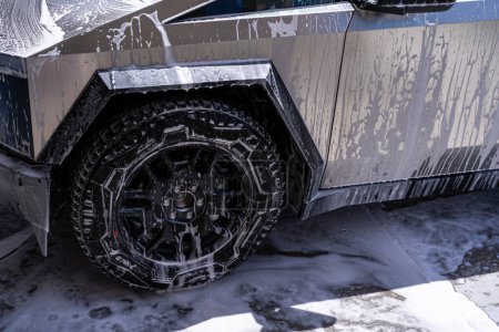 Téléchargez les photos : Denver, Colorado, États-Unis-5 mai 2024-Gros plan sur un cybercamion Tesla en train d'être lavé, montrant la conception angulaire du véhicule et les pneus robustes. Les moules à eau et à savon recouvrent la surface métallique - en image libre de droit