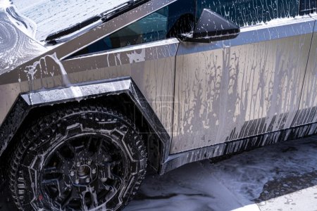Photo for Denver, Colorado, USA-May 5, 2024-Close-up image of a Tesla Cybertruck being washed, showcasing the vehicle angular design and rugged tires. Water and soap suds cover the metallic surface - Royalty Free Image