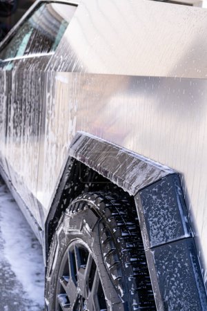 Photo for Denver, Colorado, USA-May 5, 2024-This image features a close-up view of the Tesla Cybertruck wheel and angular body design covered in soap and water during a thorough car wash, highlighting the - Royalty Free Image