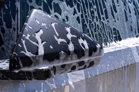 Foto de Denver, Colorado, USA-May 5, 2024-Esta imagen captura una vista cercana del espejo lateral Tesla Cybertruck cubierto de jabón durante un lavado de autos, enfatizando el diseño angular único del vehículo y - Imagen libre de derechos