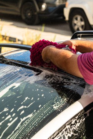Nettoyage efficace d'une voiture électrique dans le confort d'une allée de banlieue, combinant éco-conscience et praticité.