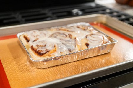 Photo for Just out of the oven, cinnamon rolls cool on a silicone baking mat, their icing glistening under the kitchen lights. - Royalty Free Image
