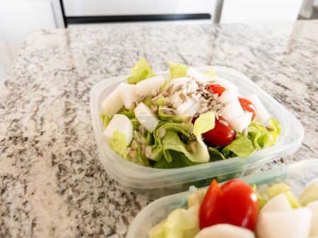 Behälter gefüllt mit Salat und Dressing, zubereitet für eine bequeme Mittagsmahlzeit.