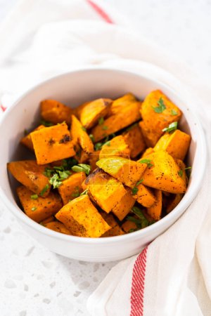 Serving oven-roasted sweet potatoes in a white ceramic bowl.