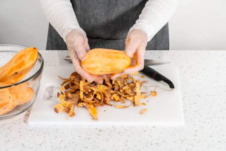 Süßkartoffeln mit einem Kartoffelschäler schälen, um im Ofen gebratene Süßkartoffeln herzustellen.