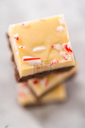 Homemade candy cane fudge square pieces on a kitchen counter.