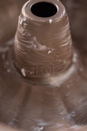 Photo for Greasing metal bundt cake pan to red velvet bundt cake with cream cheese glaze. - Royalty Free Image