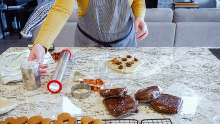 Mit einem verstellbaren Nudelholz rollt man Lebkuchenteig auf der eleganten Marmortheke in einer modernen Küche aus und macht sich bereit für das festliche Weihnachtsbacken.