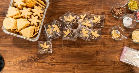 Embalaje cuidadoso galletas de Navidad recorte, medio sumergido en chocolate, espolvoreado con nueces trituradas, y presentado en envoltura de celofán transparente.