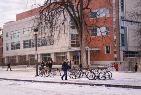 Téléchargez les photos : Winnipeg, Manitoba, Canada - 11 19 2014 : Des étudiants marchent devant le complexe de génie et de technologie de l'information de l'Université du Manitoba. Même en hiver rigoureux, les étudiants utilisent des vélos - en image libre de droit
