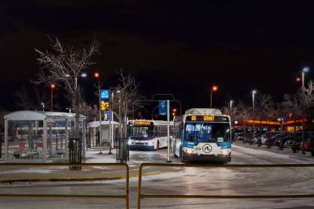 Téléchargez les photos : Winnipeg, Manitoba, Canada - 11 20 2014 : Vue de nuit de la gare routière Northbound Polo Park éclairée avec des autobus garés de Winnipeg Transit à côté d'abribus vitrés pour sauver les cyclistes des rudes - en image libre de droit