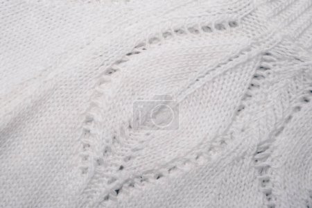 Detailed view of a soft, white knitted blanket, showing the intricate pattern and texture of the fabric.