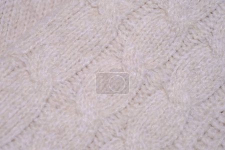 A detailed view of a white knitted blanket showcasing its intricate pattern and texture in a close-up shot.