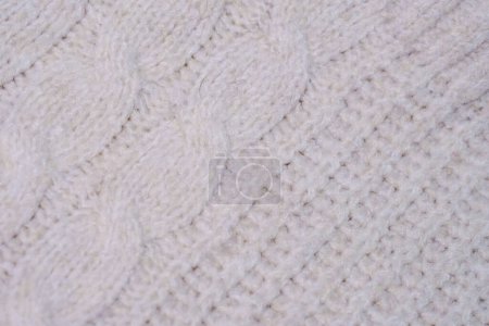 Vue détaillée d'une couverture en tricot blanc présentant des points et des textures complexes.