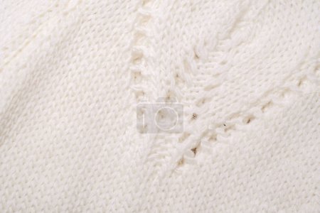 Ein detaillierter Blick auf einen weißen Strickpullover, der seine komplizierte Textur zur Geltung bringt und aus nächster Nähe näht.