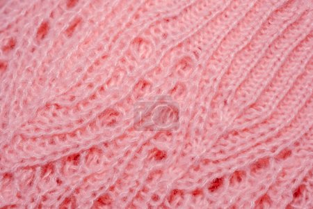 Detailed view of a soft pink knitted blanket, showcasing intricate patterns and textures up close.