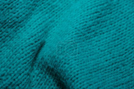 Una vista detallada de un suéter de color verde azulado, mostrando su textura y patrón de punto. La prenda parece ser suave y bien hecha.