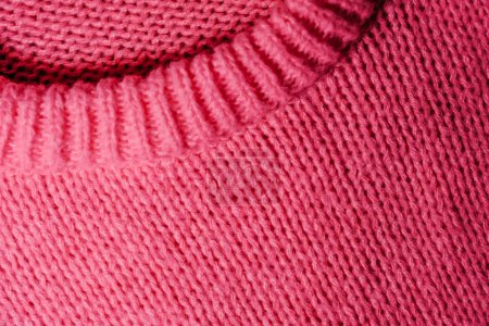 A detailed view of a pink sweater with a noticeable hole in the center, showcasing the texture and color of the fabric.