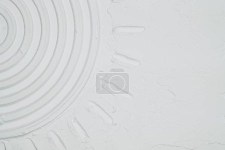 Eine weiße Wand mit einem präzisen kreisförmigen Design in der Mitte, die einen optisch markanten Mittelpunkt im Raum schafft.