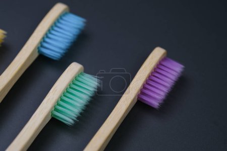 Photo for Three toothbrushes of different colors are lined up neatly next to each other on a wooden table. - Royalty Free Image