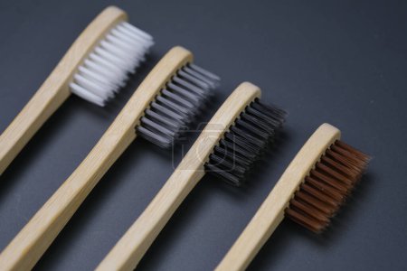 Téléchargez les photos : Trois brosses à dents sont soigneusement alignées sur une table en bois. Chaque brosse à dents a différentes poils de couleur, créant une composition visuellement intéressante. - en image libre de droit
