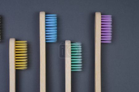 Four toothbrushes are neatly lined up against a plain gray background, showcasing their colorful bristles and grips.