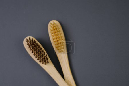 Two wooden toothbrushes are placed next to each other on a surface.
