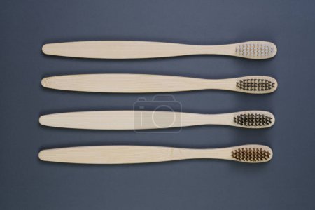 Three wooden toothbrushes are neatly lined up next to each other on a flat surface, showcasing simplicity and eco-friendly dental care.