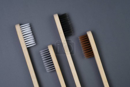 Téléchargez les photos : Trois brosses à dents sont placées en rangée sur une table en bois. Les soies sont propres et bien disposées, prêtes à l'emploi. - en image libre de droit