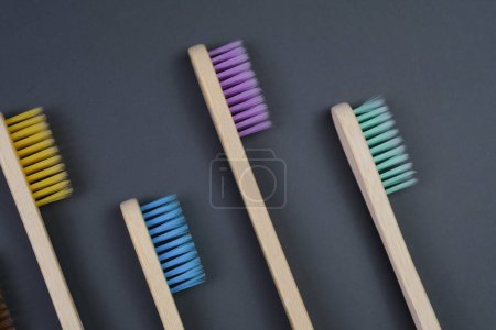 Three toothbrushes of different colors lined up neatly next to each other on a white countertop.