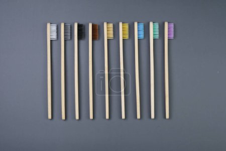 A composition of five toothbrushes with various colors neatly lined up in a row on a flat surface.