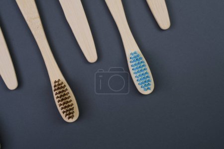 Cuatro cepillos de dientes de madera están perfectamente alineados en una fila sobre una superficie plana, mostrando su diseño sostenible y respetuoso con el medio ambiente.