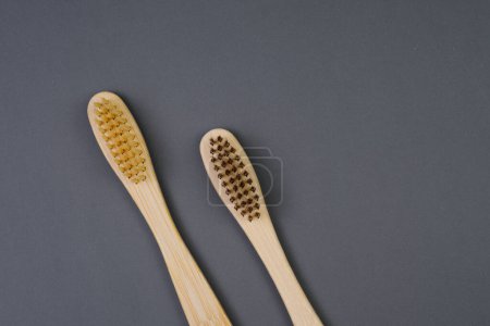 Two wooden toothbrushes made of sustainable materials are placed next to each other on a flat surface.