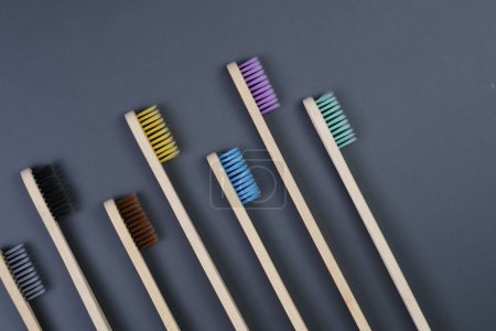 Five toothbrushes are neatly lined up in a row on a smooth gray surface.