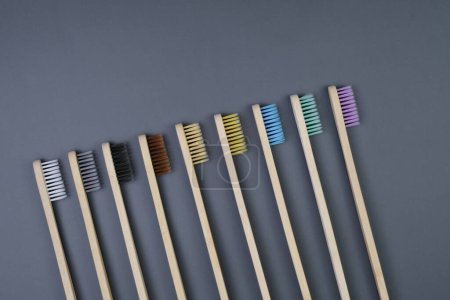 Téléchargez les photos : Une gamme de différentes brosses à dents multicolores soigneusement disposées en rangée sur un fond gris uni. - en image libre de droit