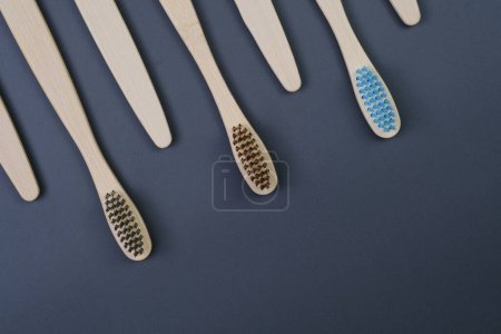 Five toothbrushes are neatly arranged in a row on a smooth blue surface, creating a visually pleasing and organized display.