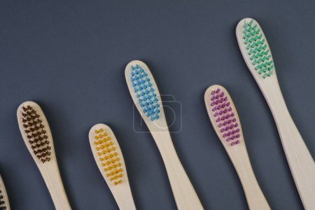 Téléchargez les photos : Cinq brosses à dents sont soigneusement alignées en rang sur une table en bois, mettant en valeur leurs poignées et soies colorées. - en image libre de droit