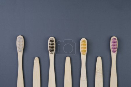 Five toothbrushes of various colors neatly arranged in a straight line on a flat surface.