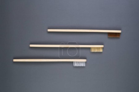 Three wooden combs laying on a plain gray surface, showcasing their simple and functional design.