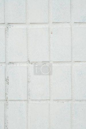 Téléchargez les photos : Un mur de carrelage blanc avec de petits motifs carrés, créant un décor géométrique et propre dans une pièce ou un bâtiment. - en image libre de droit