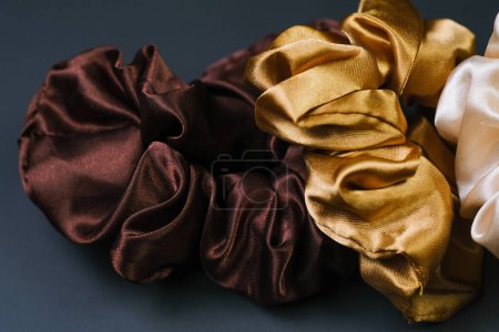 Photo for A detailed view of three colorful scrunchies placed neatly on a wooden table, showcasing their textures and colors. - Royalty Free Image