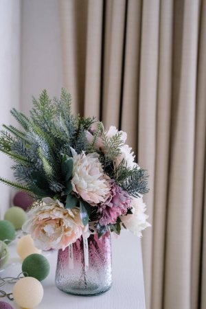 Un jarrón de cerámica lleno de flores de colores se sienta sobre una mesa de madera, creando una pieza central vibrante y animada en la habitación.