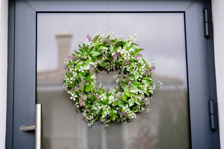 Téléchargez les photos : Une couronne verte est suspendue sur une porte en bois, ajoutant une touche de décoration à l'entrée d'un bâtiment. - en image libre de droit
