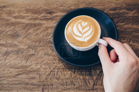 Foto de Vista recortada de la mano humana con una taza de café con leche caliente. - Imagen libre de derechos