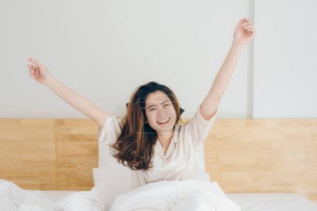 Foto de Retrato de mujer asiática con sensación de felicidad después de despertarse por la mañana en el dormitorio del hotel. Conceptual de la mujer estilo de vida. - Imagen libre de derechos