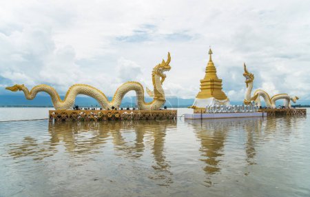 Foto de La pagoda dorada y Twin Naga un hito icónico en el lago Phayao, Tailandia. (El texto en la base de la pagoda es medio viaje en Phayao es muy divertido) - Imagen libre de derechos