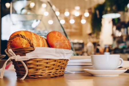 Foto de Vista recortada de una taza de café con una cesta de pan en la cafetería. - Imagen libre de derechos